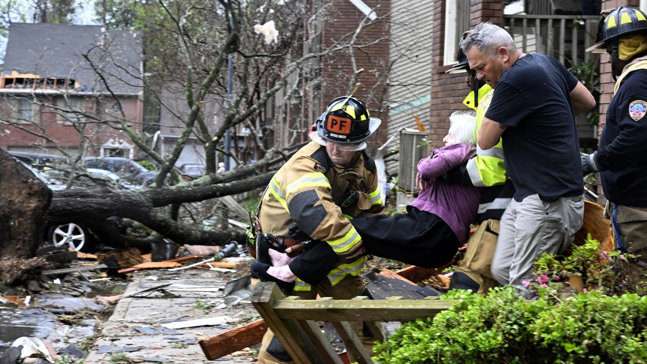 Firefighters carry a woman out of her condo after her complex was damaged by a tornado on Friday, March 31, in Little Rock, Arkansas. 