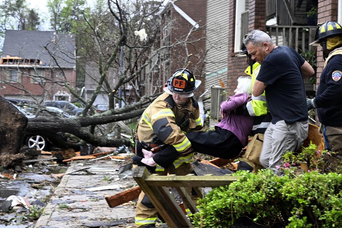 Firefighters carry a woman out of her condo after her complex was damaged by a tornado on Friday, March 31, in Little Rock, Arkansas. 