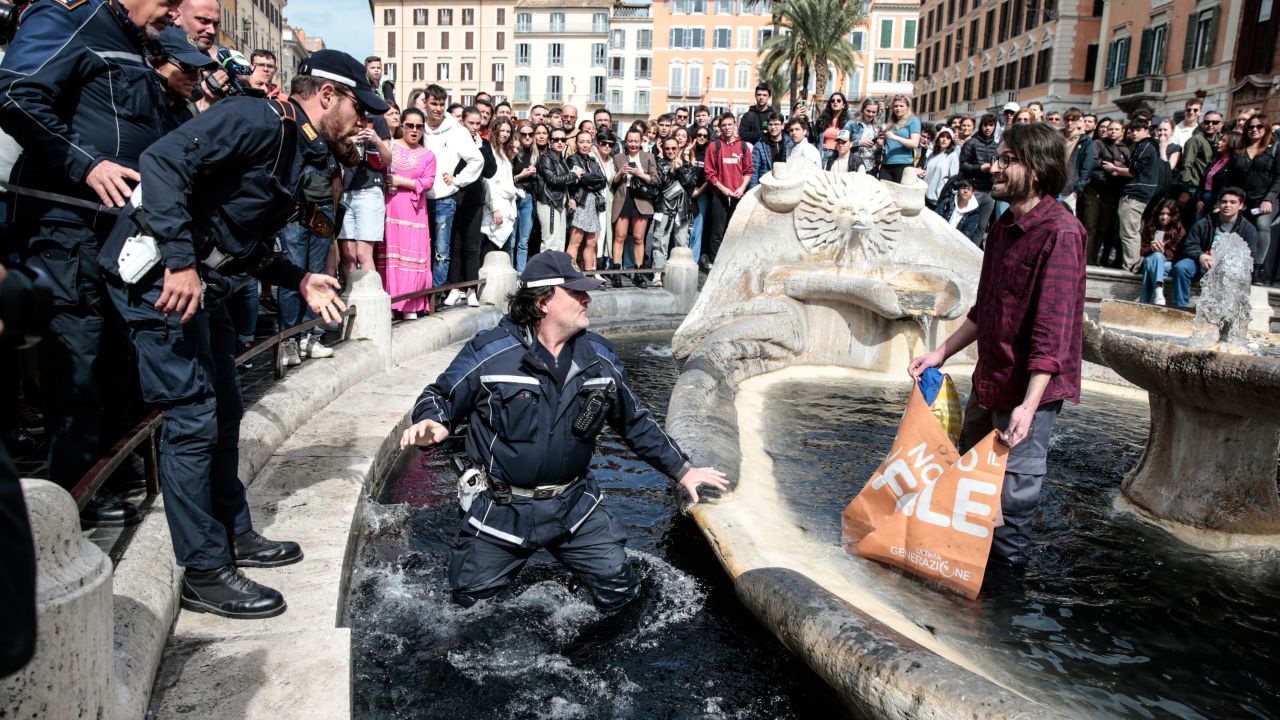 A police officer enters the fountain to remove an environmental activist.