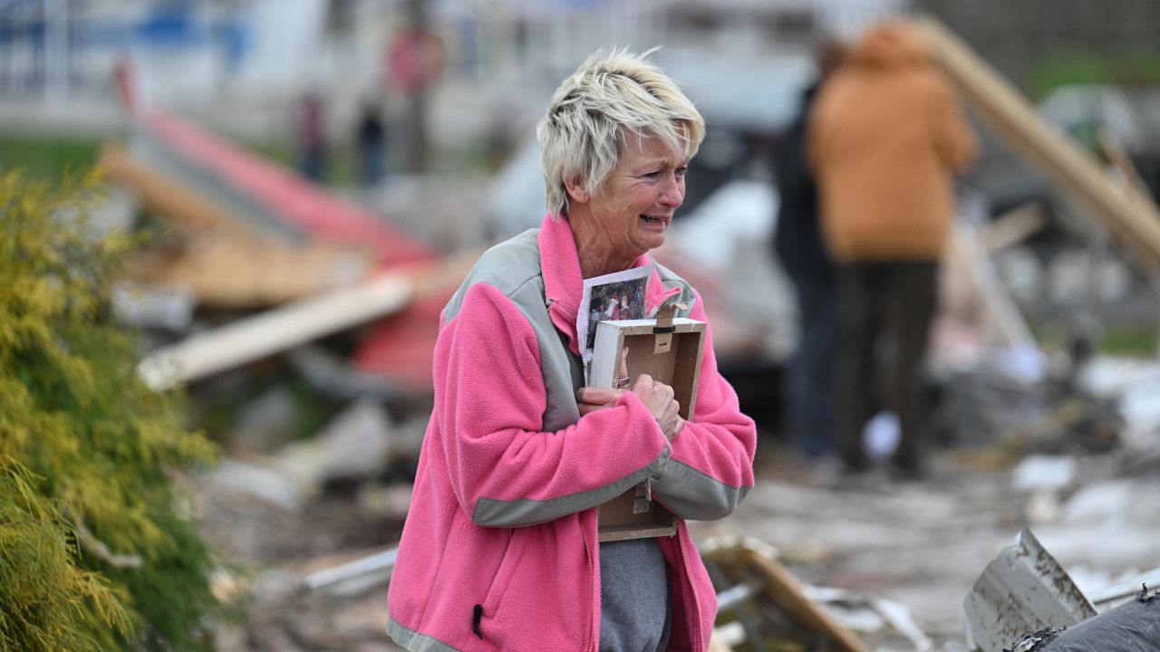 Debbie Lowdermilk holds photographs as she reacts while looking at the destroyed school she owns the day after a reported tornado hit Sullivan, Indiana.