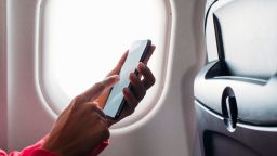 Close up shot of an unrecognisable woman's hand while holding a phone in an airplane