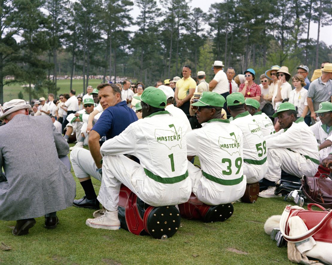 Palmer looks over his shoulder as he sits with a group of caddies during the 1965 Masters.