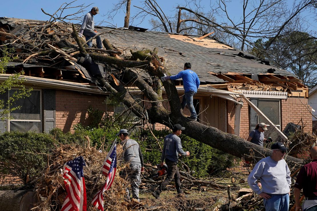 After a tornado struck Little Rock, Arkansas, people work to remove a tree that fell on top of a home Sunday.