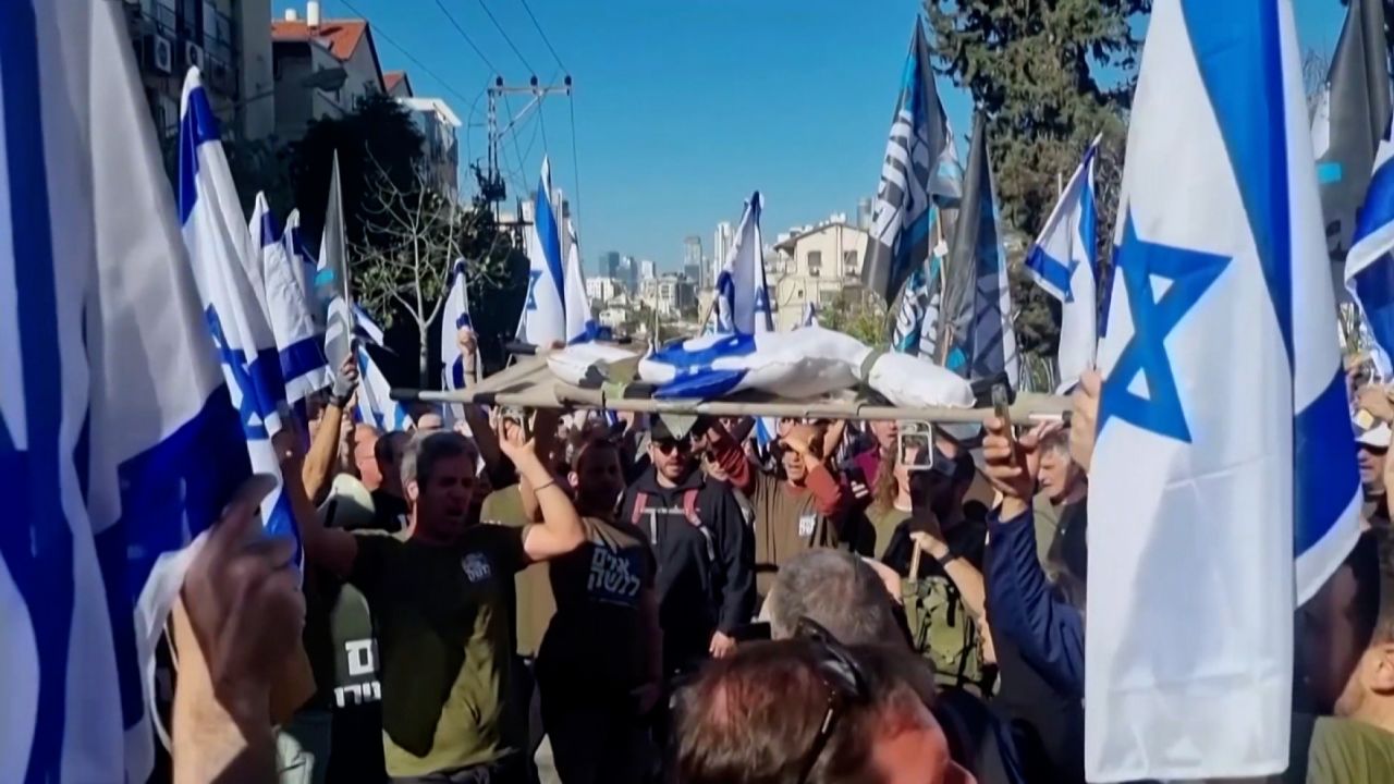 A group from Brothers and Sisters in Arms protests by carrying a figure wrapped in the Israeli flag on a stretcher, the way they would carry a wounded comrade off the field.