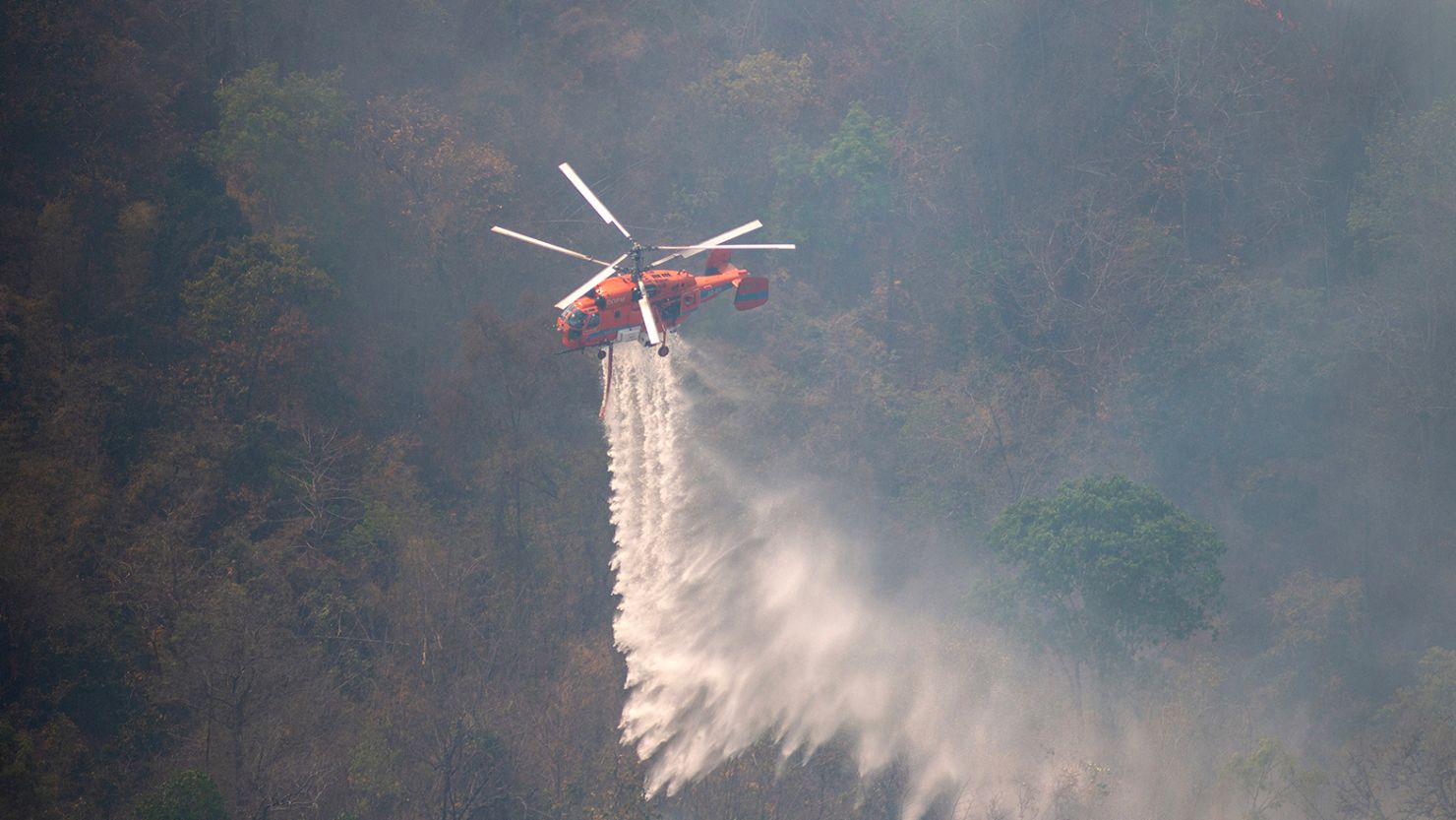 A firefighting helicopter extinguishing a forest fire in Chiang Mai, Thailand on March 29, 2023. 