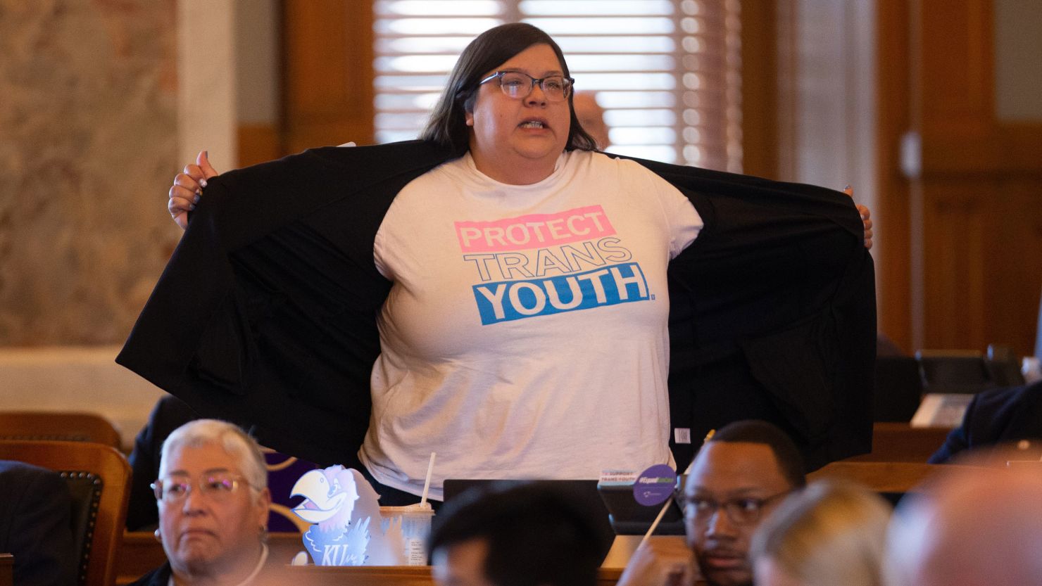 Rep. Heather Meyer shows her "protect trans youth" t-shirt to legislature members following Wednesday's vote to override Gov. Laura Kelly's veto of an anti-trans sports bill. 