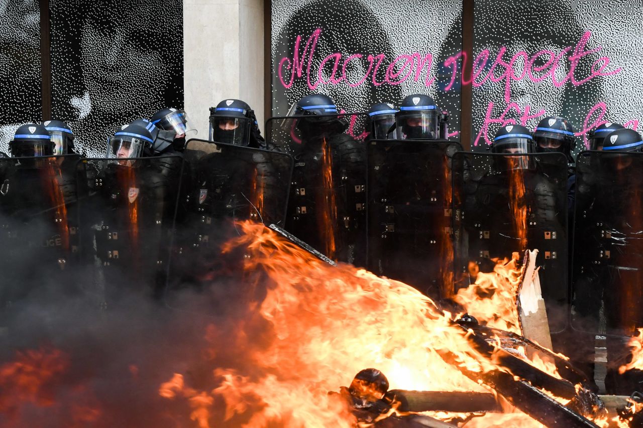 Police form a cordon between a vandalized shop window and a fire that was set on the street during demonstrations in Paris on Thursday, April 6. There have been nationwide protests in France since the government raised the retirement age for most workers from 62 to 64.