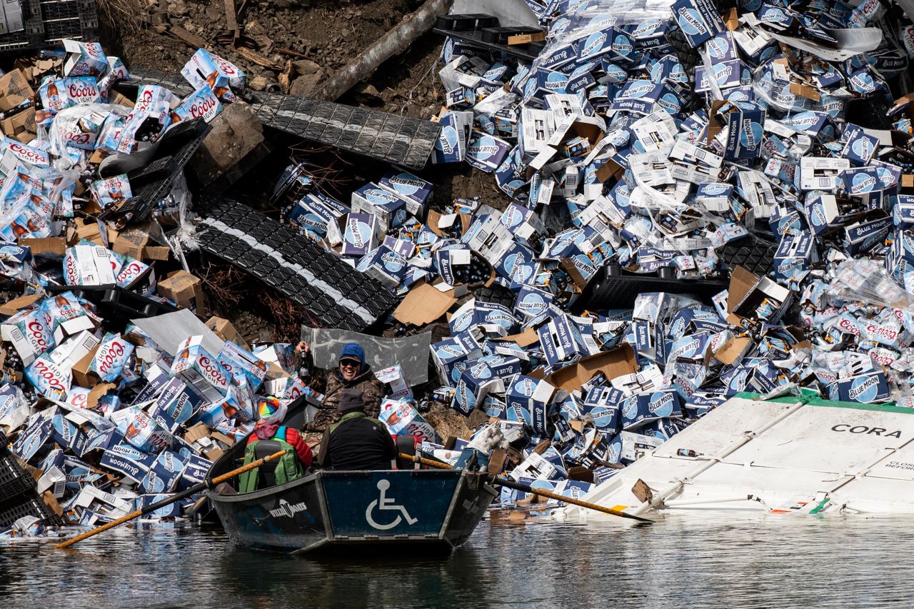 Fishermen claim a bottle of beer from a derailed rail car on the banks of the Clark Fork River in Montana on Sunday, April 2. A freight train derailed with approximately 25 cars. No injuries were reported.