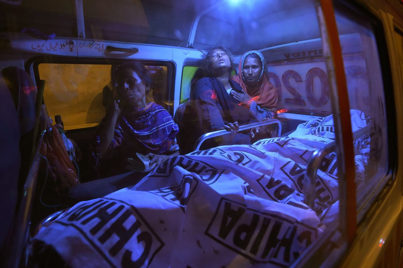 People in an ambulance mourn next to the body of a family member who died in a crowd crush in Karachi, Pakistan, on Friday, March 31. At least 13 people were killed and 10 were injured in the crush, which happened among people waiting for Ramadan food donations.