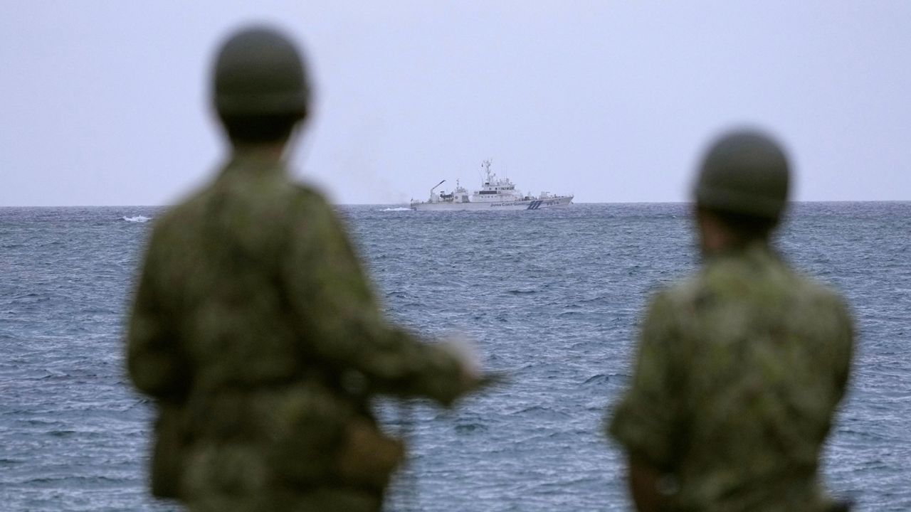 A Japan Coast Guard vessel conducts search and rescue operation at the site of a military helicopter crash as Japan Self-Defense Force members look on, in Miyakojima, Okinawa prefecture, Japan.