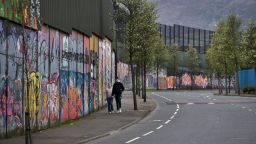 A couple walk along a "peace wall" in Belfast, Northern Ireland.
