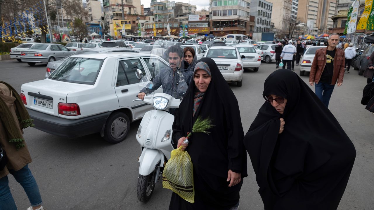 A veiled Iranian woman walks along a square with her relative in northern Tehran on March 17, 2023.