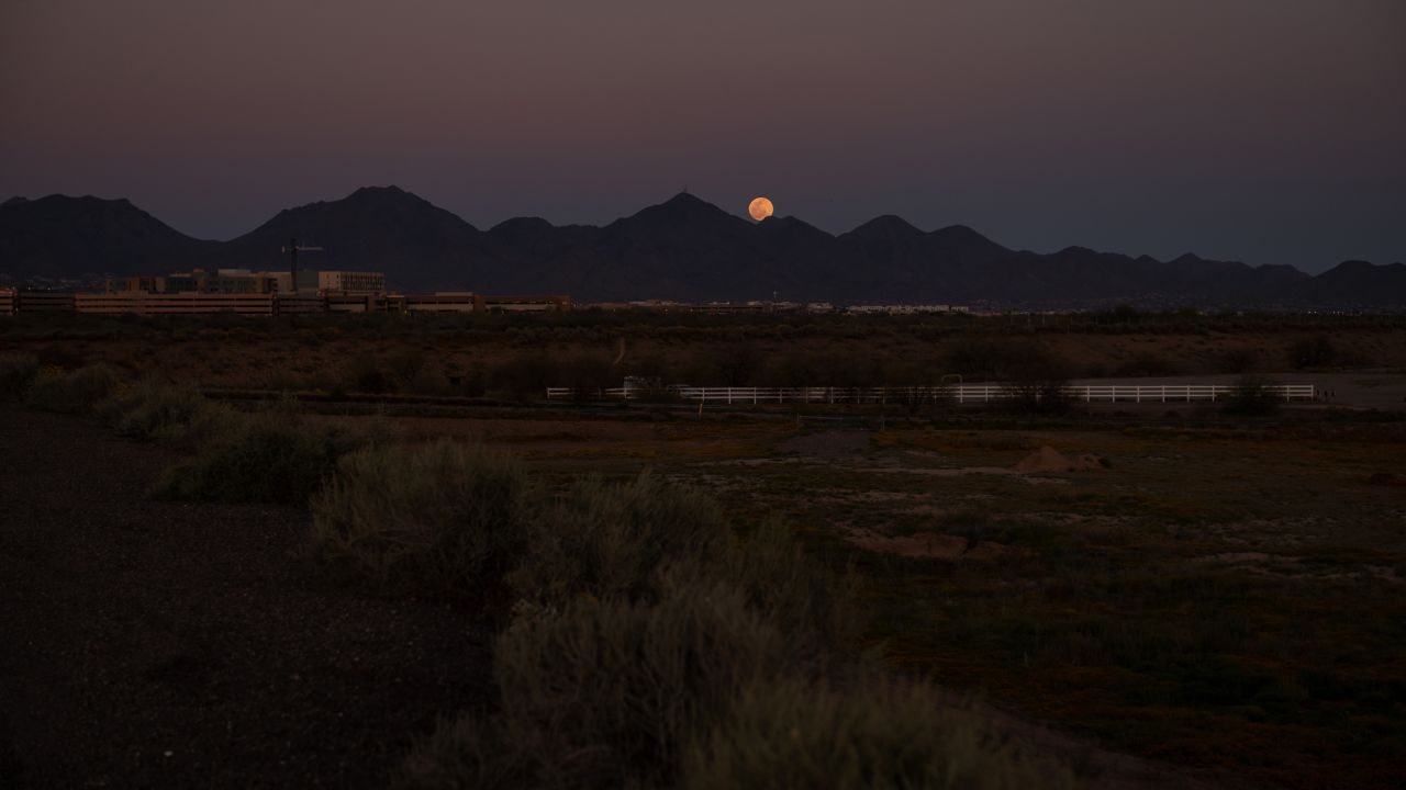 A full moon rises over mountains in Phoenix.