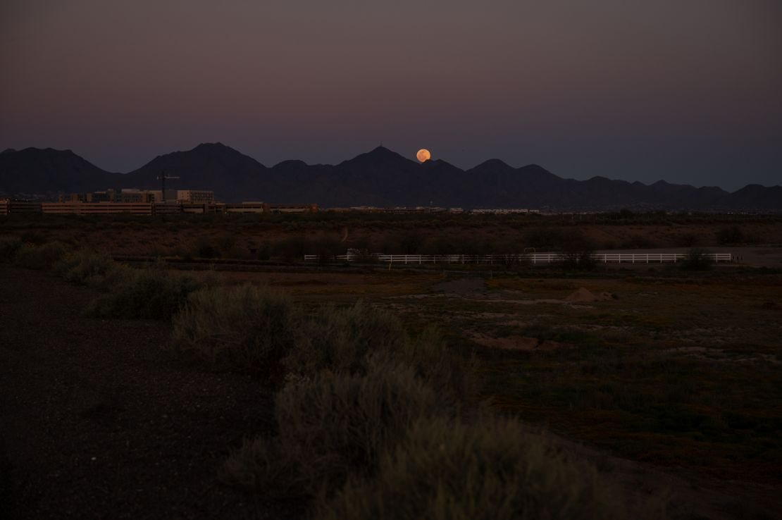A full moon rises over mountains in Phoenix.