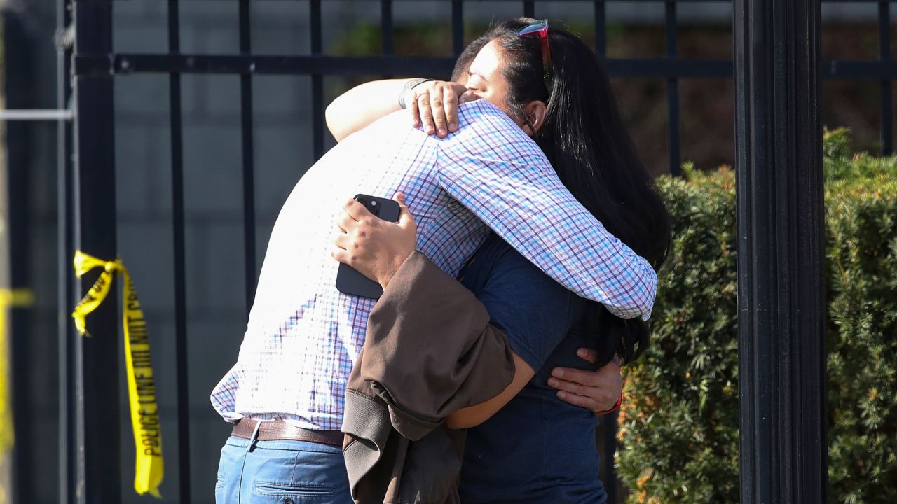 Zwei Menschen umarmen sich vor dem Gebäude, in dem am Montag in Louisville eine Massenerschießung stattfand.