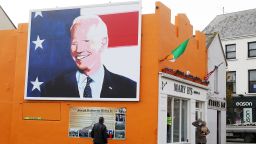 In this November 2020 photo, a man stops to read a plaque below a mural of then-Presidential candidate Joe Biden in his ancestral home of Ballina in north County Mayo, Ireland.