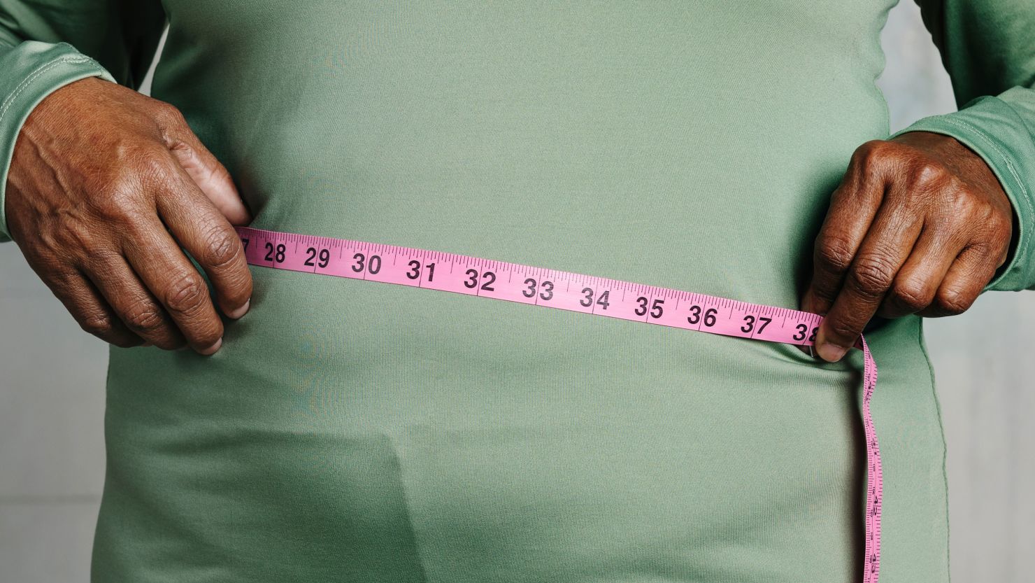 Measuring tape, stomach and woman in studio for wellness, weight