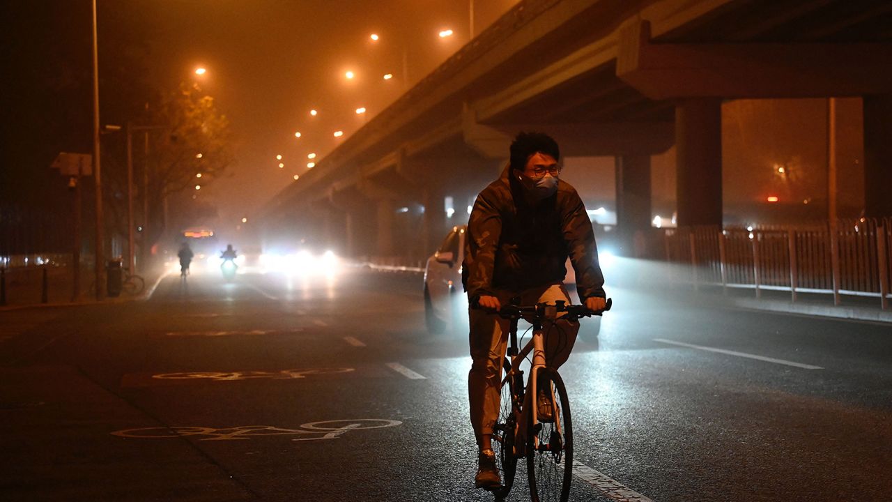 مردی در 10 آوریل 2023 هنگام طوفان شن در پکن در امتداد خیابانی دوچرخه سواری می کند. 