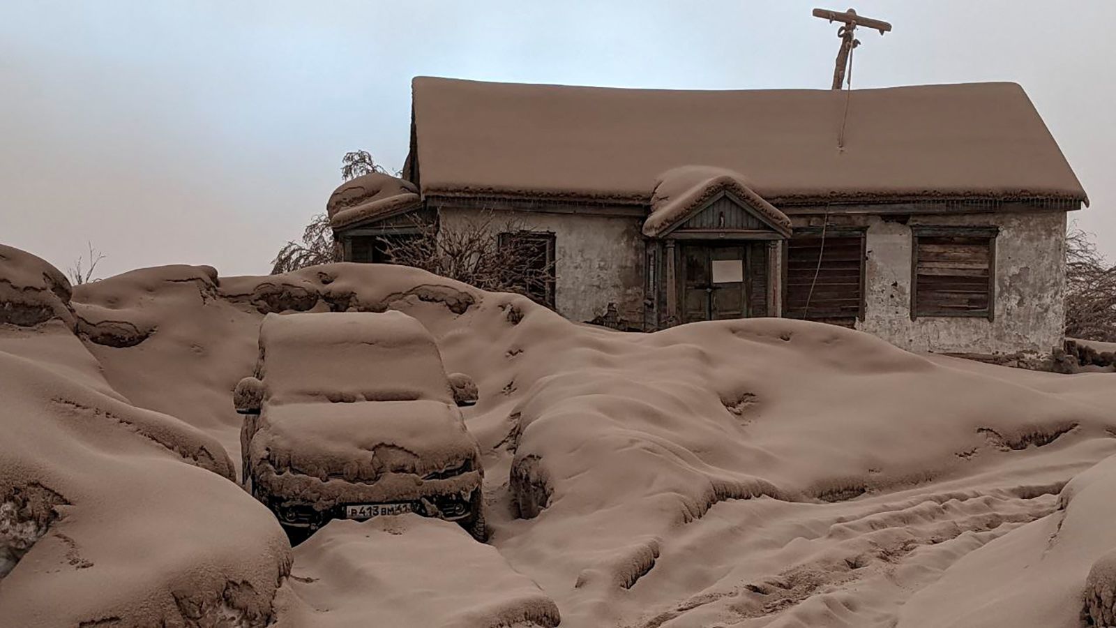 A house and a car are covered in volcanic dust Tuesday, April 11, after the eruption of the Shiveluch volcano in Russia's far eastern Kamchatka region.