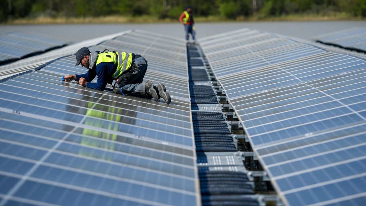 A worker fixes solar panels at a floating photovoltaic plant on the Silbersee lake in Haltern, western Germany.