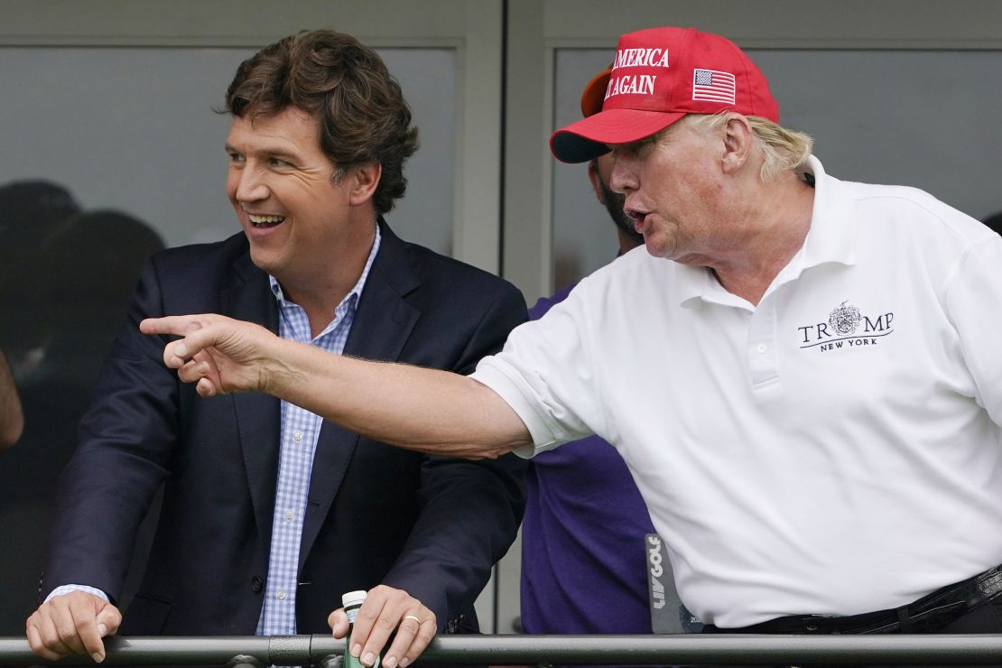 Tucker Carlson, left, and former President Donald Trump, talk while watching golf.