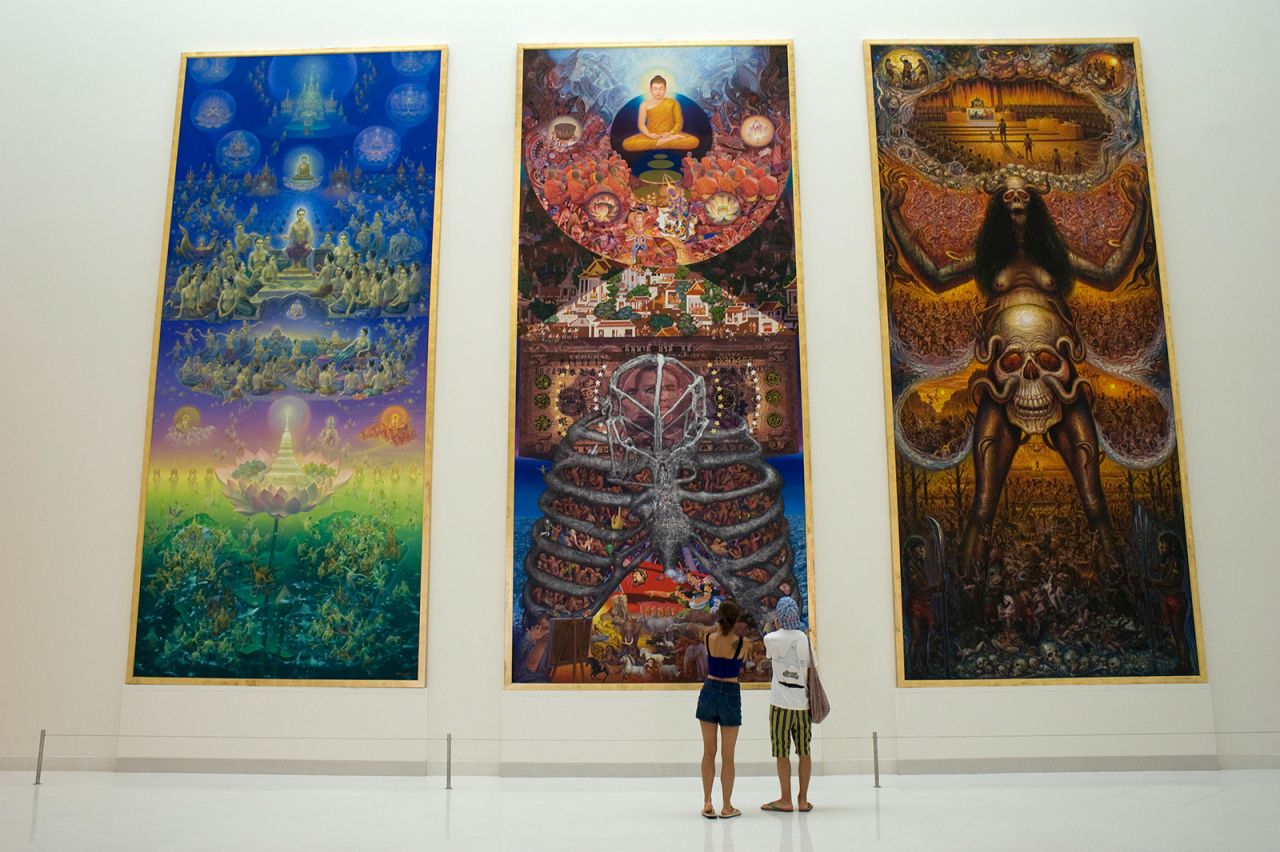 Visitors look at an installation, three huge commissioned paintings about Buddhism and materialism inside the six-story Museum of Contemporary Art, or MOCA, in Bangkok, Thailand.