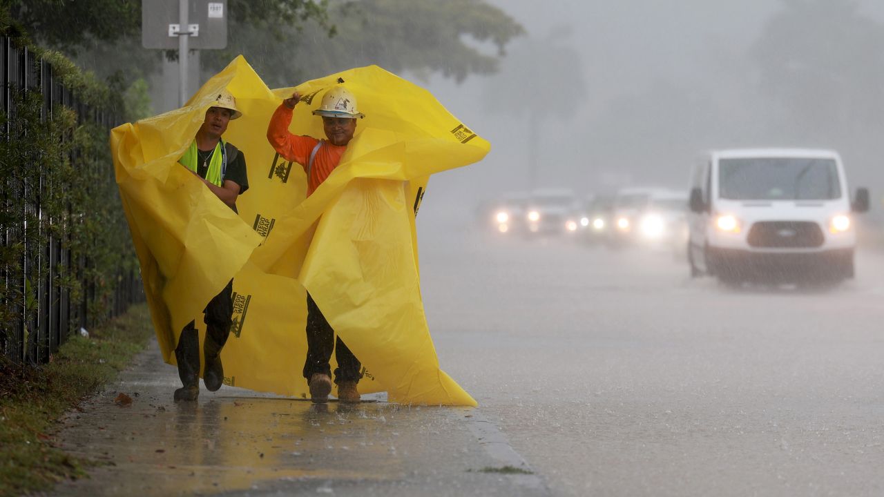 DANIA BEACH, FLORIDA - APRIL 12: Workers use a tarp to protect themselves from the rain on April 12, 2023 in Dania Beach, Florida. Heavy rain passed through the South Florida area causing some area flooding. (Photo by Joe Raedle/Getty Images)
