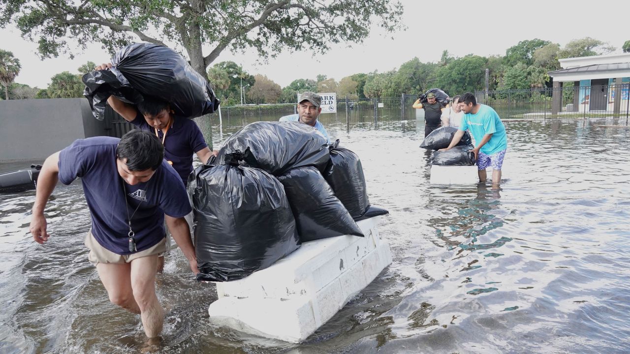 Orang ramai mencuba dan menyelamatkan barang berharga, mengharungi air banjir yang tinggi di kawasan kejiranan Fort Lauderdale, Fla., pada Khamis, 13 April 2023.  