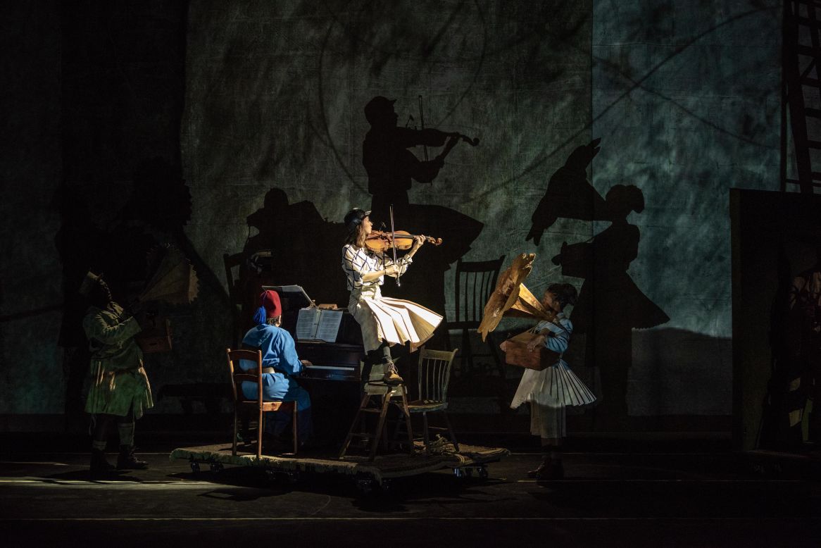 Performers create larger-than-life shadows on the stage screen, symbolizing the looming darkness of untold histories.