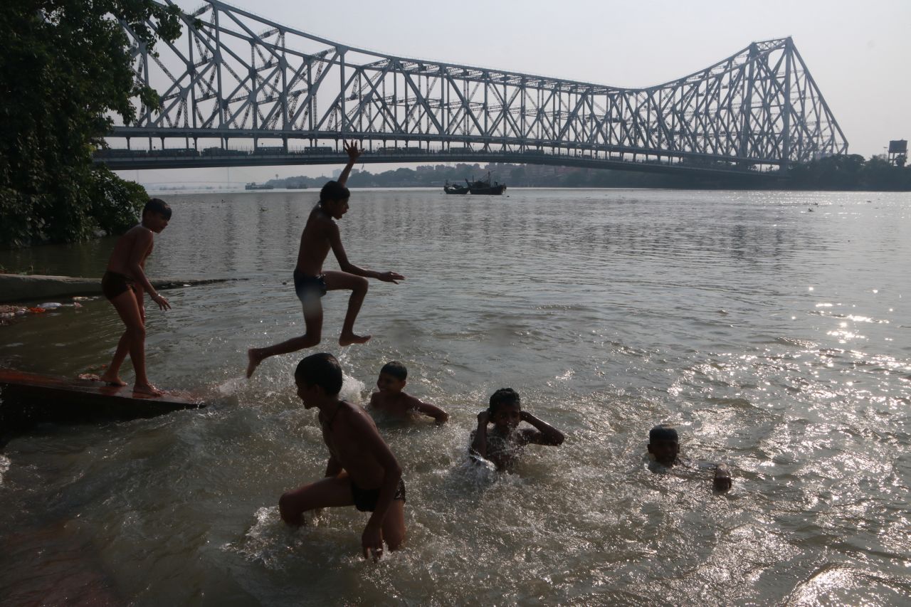 A boy jumps into the Ganges river, in front of the Howrah Bridge, on a hot day in Kolkata, India, on Monday, April 10.