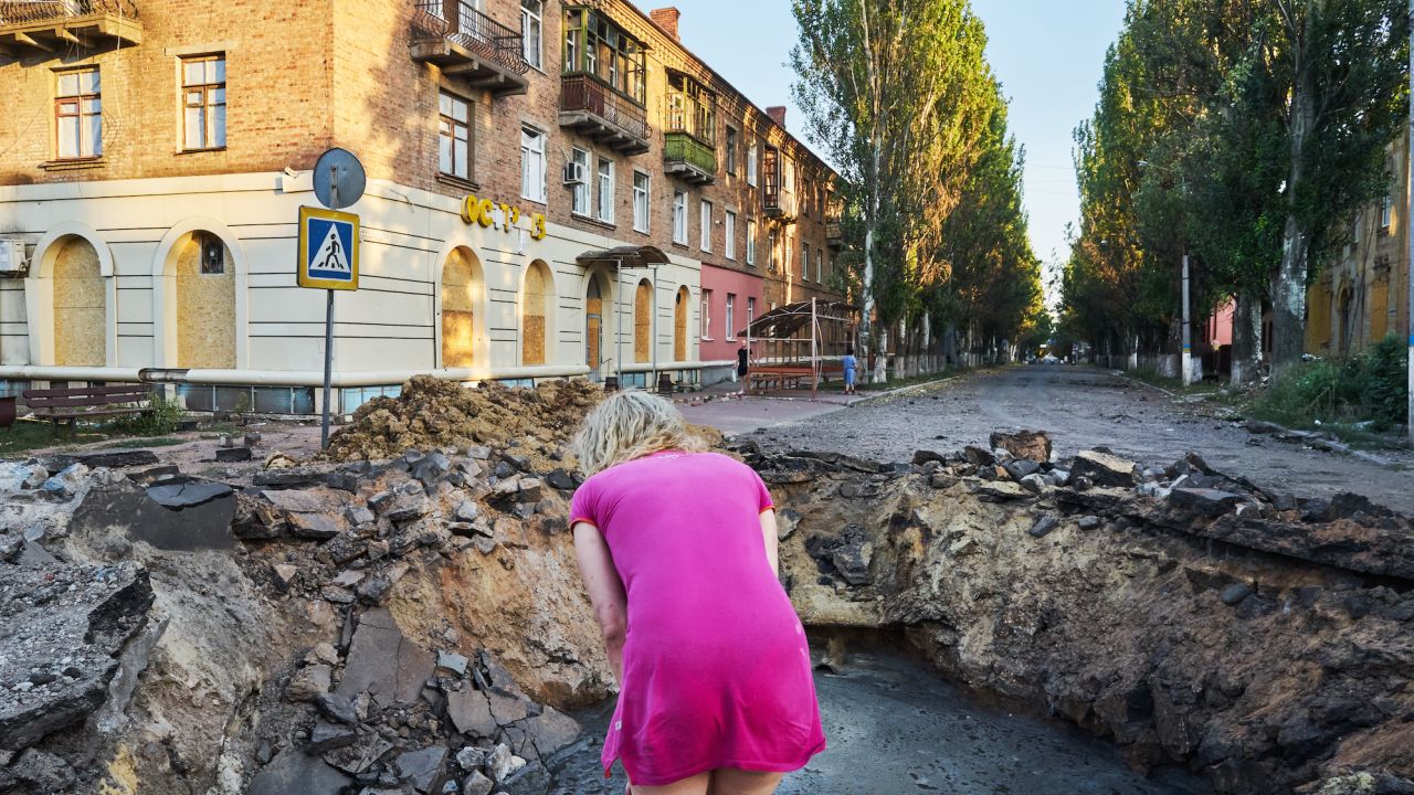 امرأة تنظر إلى الحفرة بعد أن أصاب صاروخ إسكندر-إم شارعًا في باخموت في 27 يوليو / تموز 2022.  