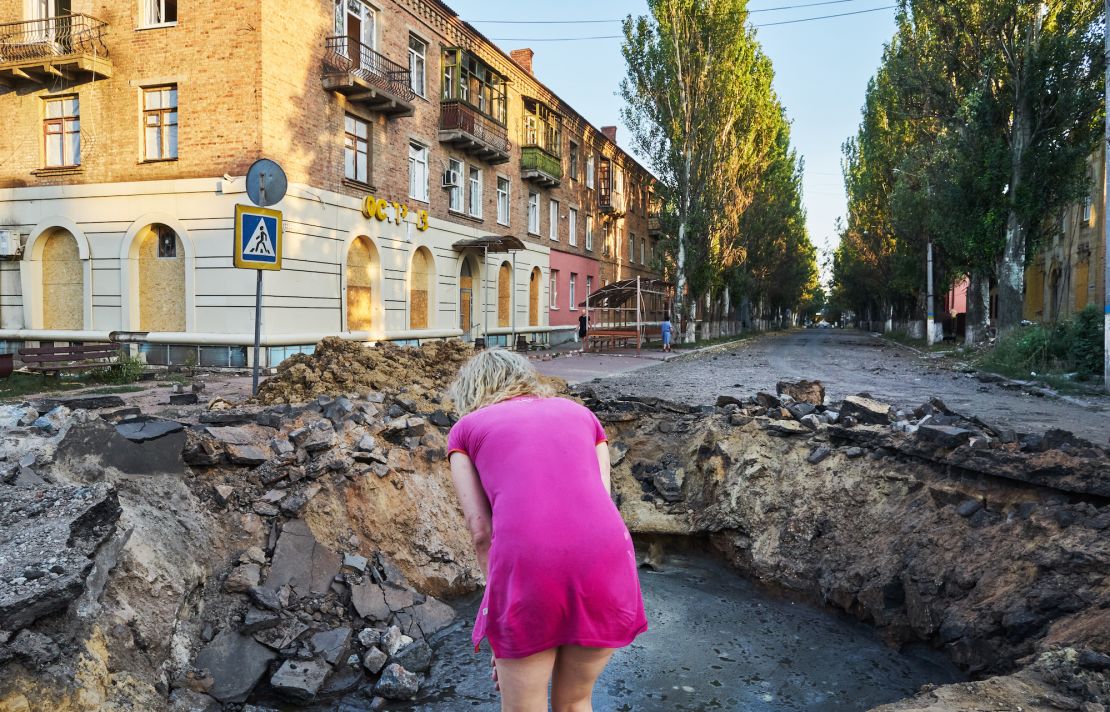 A woman looking at the crater left after an Iskander-M missile hit a street in Bakhmut on July 27, 2022.  