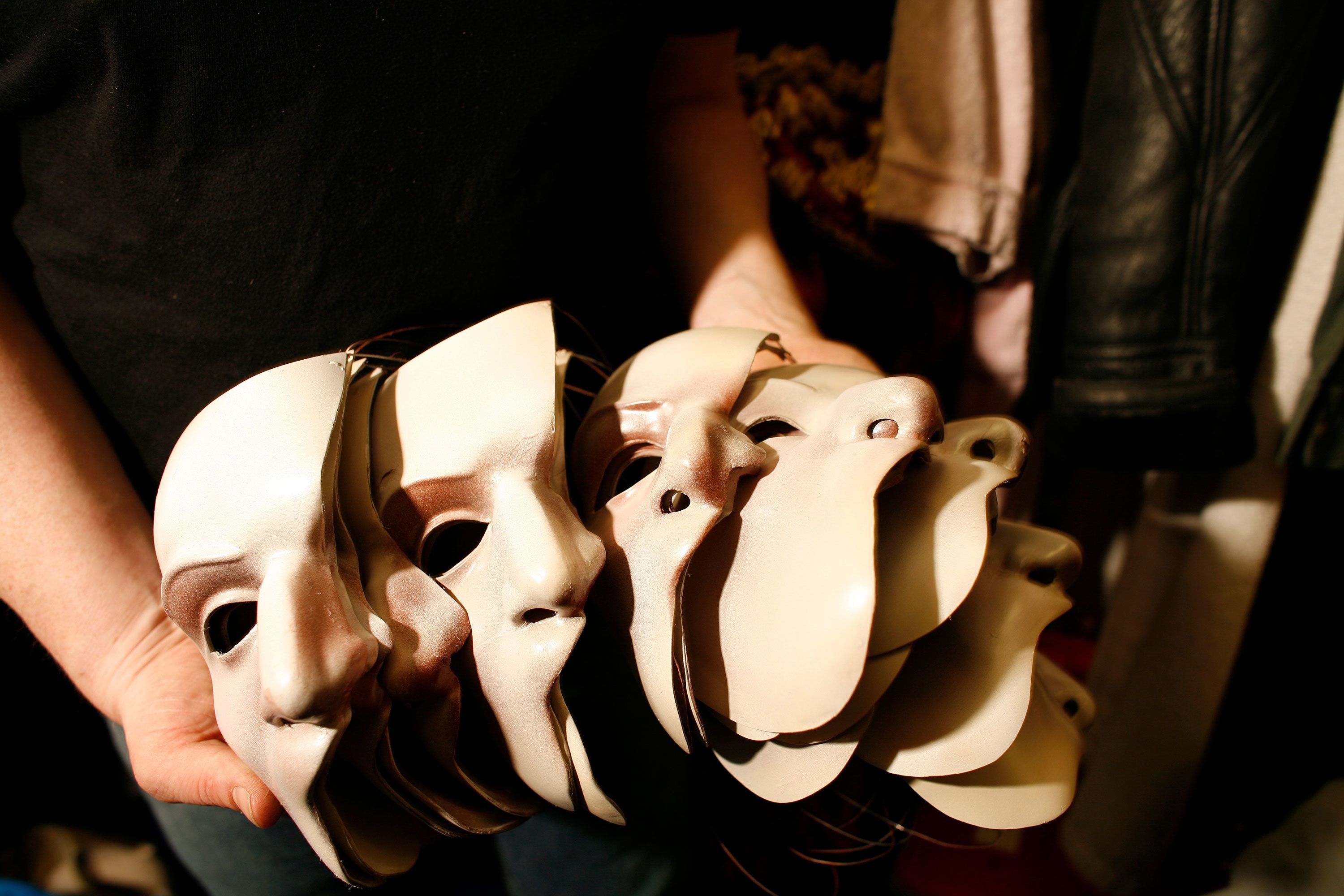 A crew member holds phantom masks backstage.