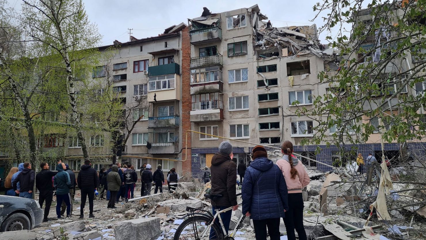 Local residents stand next to an apartment building damaged by a Russian military strike in Sloviansk, eastern Ukraine on April 14, 2023.