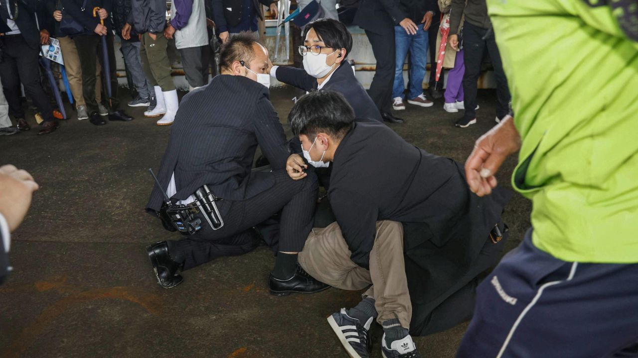 A man is held by police officers after an object was thrown near Japanese Prime Minister Fumio Kishida during a speech in Wakayama, Japan, on April 15, 2023.