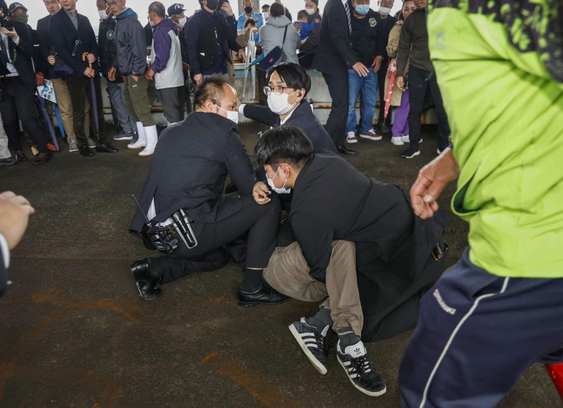 A man is held by police officers after an object was thrown near Japanese Prime Minister Fumio Kishida during a speech in Wakayama, Japan, on April 15, 2023.