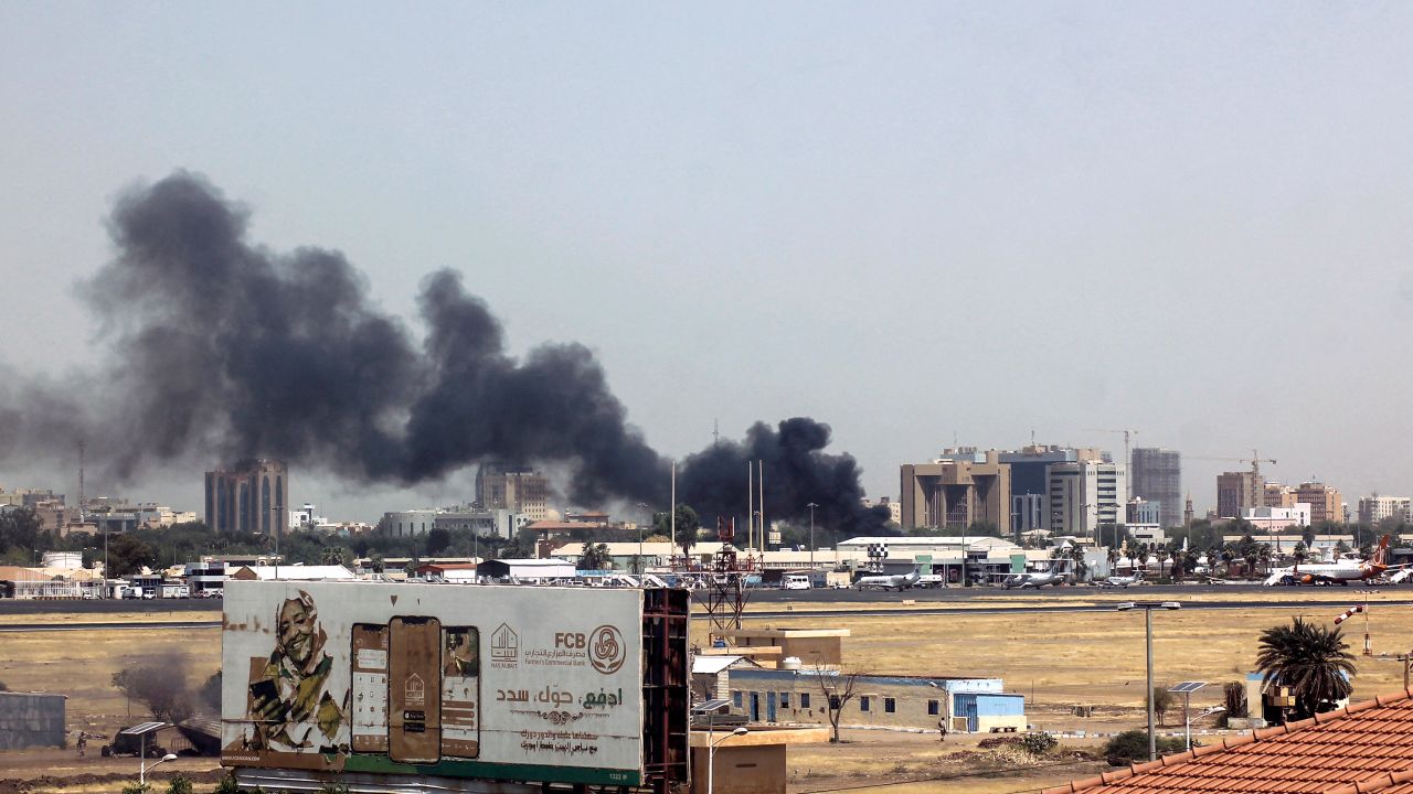 Asap tebal berkepul di atas bangunan di sekitar lapangan terbang Khartoum pada 15 April 2023, di tengah-tengah pertempuran di ibu negara Sudan.