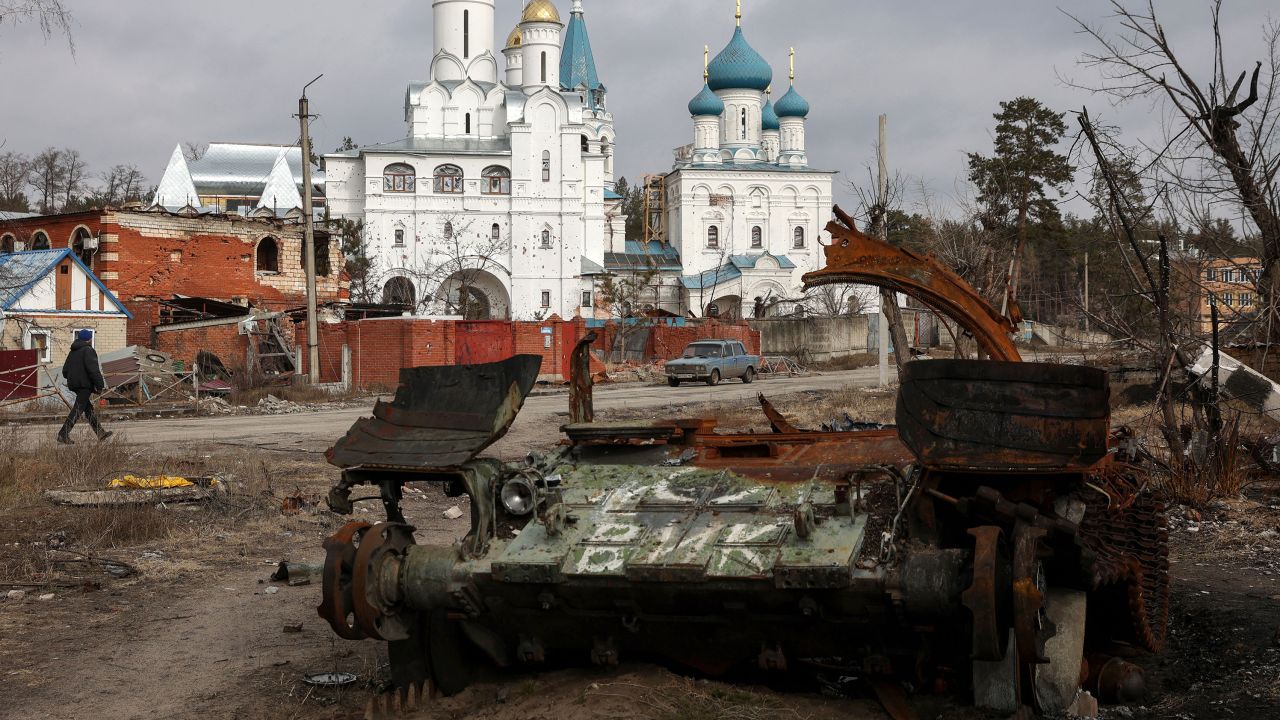 A local resident walks past a damaged church and a destroyed Russian tank in the town of Svyatogirsk, Donetsk region, on March 1, 2023. 