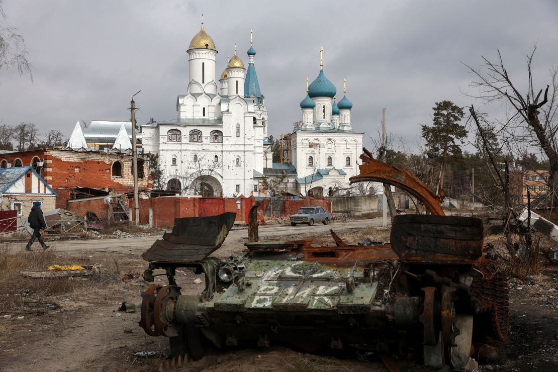 A local resident walks past a damaged church and a destroyed Russian tank in the town of Svyatogirsk, Donetsk region, on March 1, 2023. 