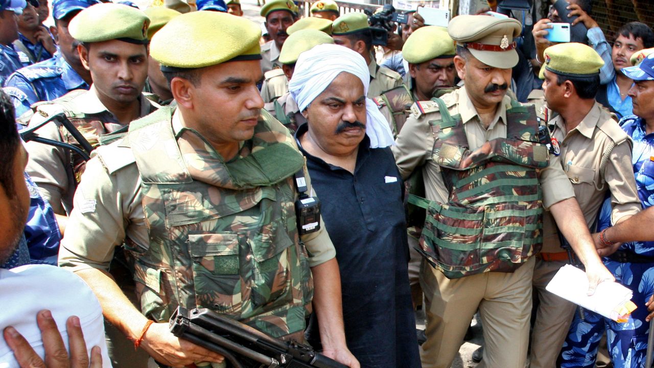 Police officers escort Atiq Ahmed outside a court in Prayagraj, India, April 13, 2023, two days before he was assassinated alongside his brother