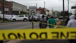 Community members watch as crime scene investigators work the scene of a shooting on April 16, 2023 in Dadeville, Alabama. According to reports, at least four people were killed and others injured in a shooting during a birthday party at a dance studio on Saturday night. 