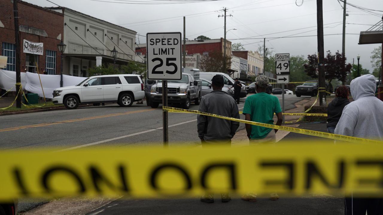 Community members watch as crime scene investigators work the scene of a shooting on April 16, 2023, in Dadeville, Alabama.