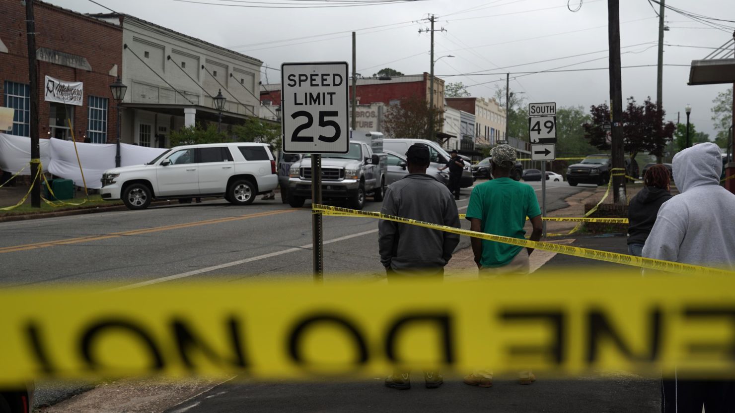 Community members watch as crime scene investigators work on the scene of a shooting in Dadeville, Alabama, where four people were killed. 