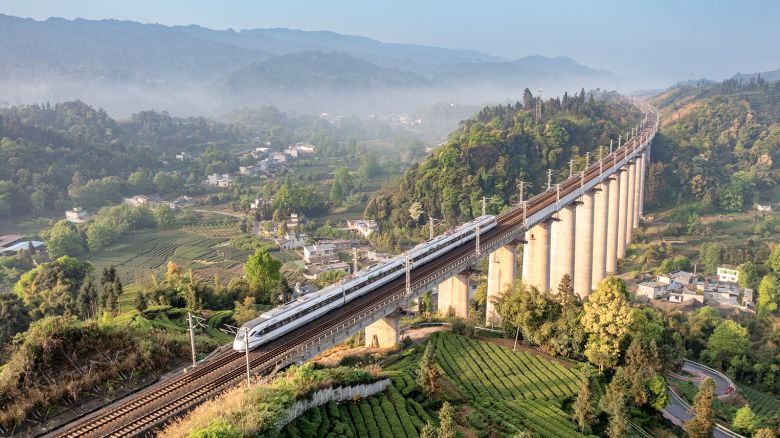A bullet train runs through a tea garden on April 12, 2023 in Yan'an, Sichuan Province of China.