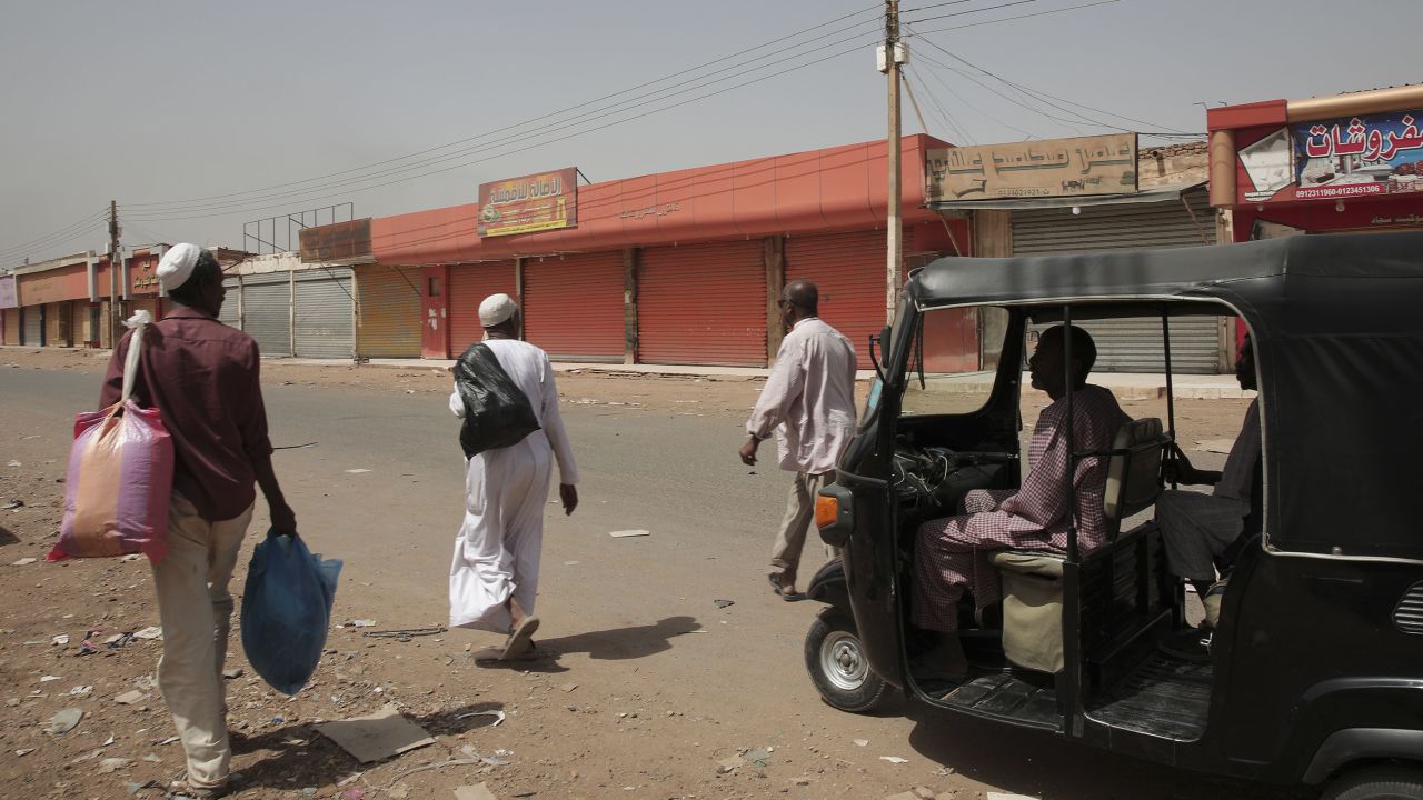People walk past shuttered shops in Khartoum, Sudan, Monday, April 17, 2023.