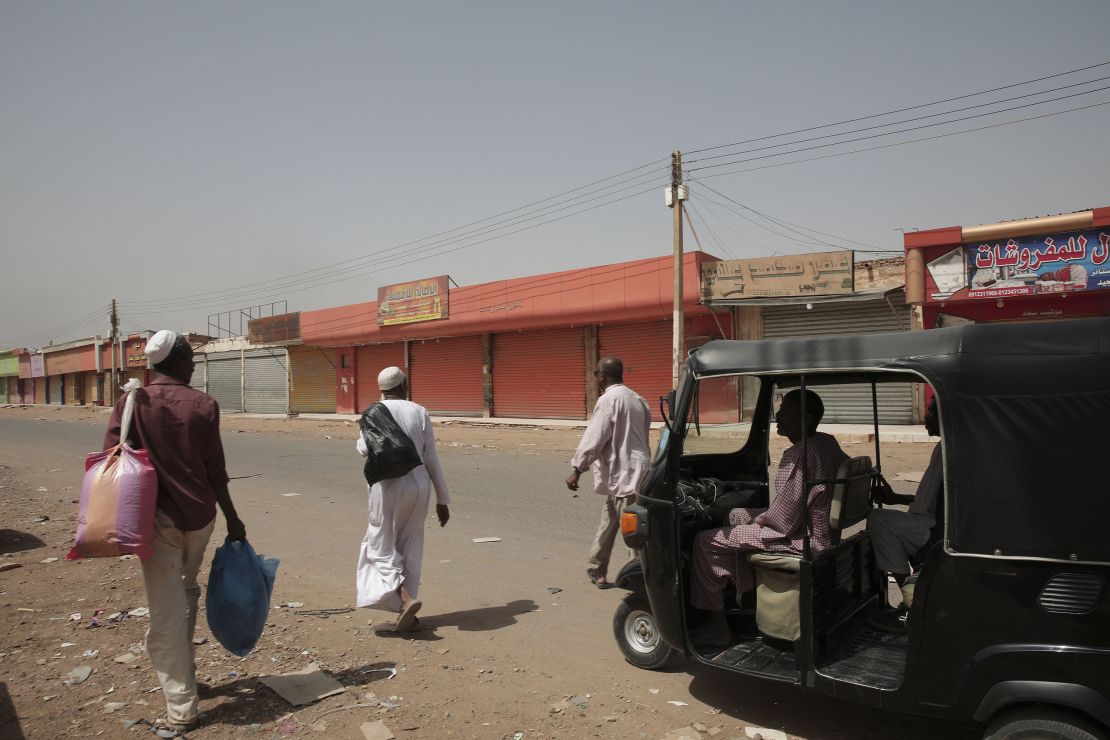 People walk past shuttered shops in Khartoum, Sudan, Monday, April 17, 2023.