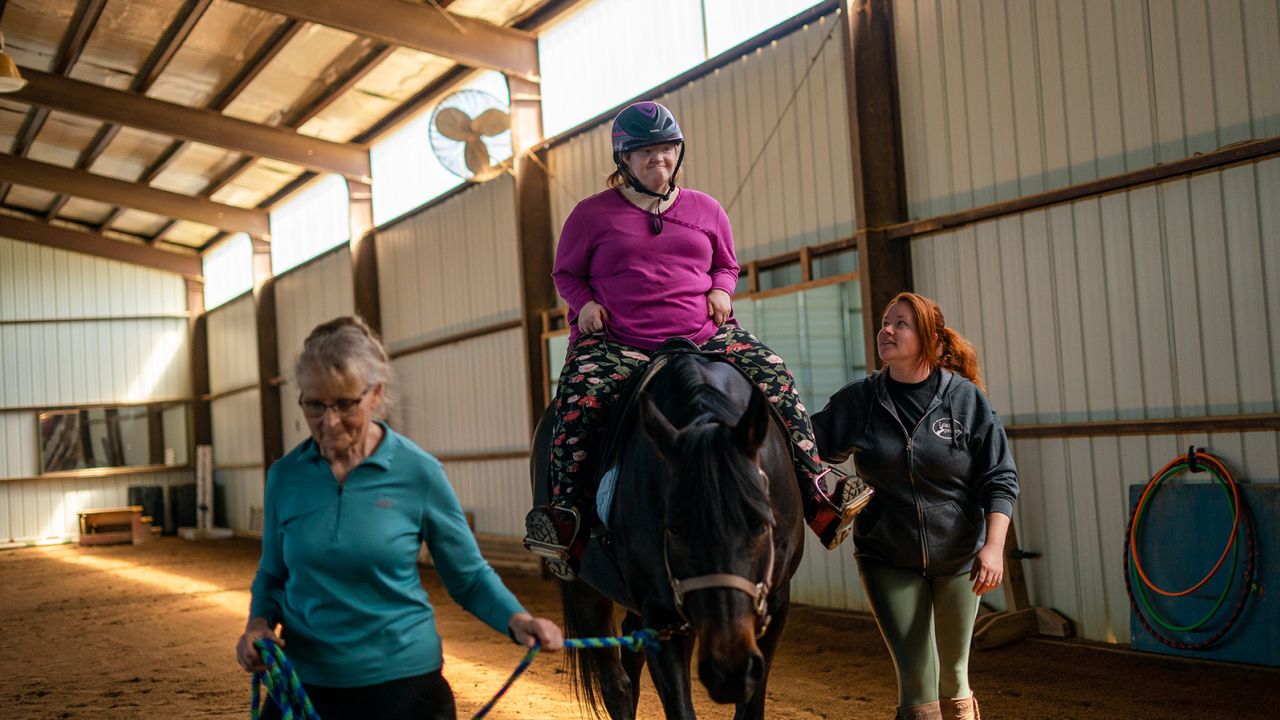 Samantha "Sammee" Lesmeister, of Montrose, Missouri, rides a horse with the help of instructors Rike Mueller, left, and Samantha Richardson at Remember to Dream, a therapeutic riding center in Cole Camp, Missouri. 