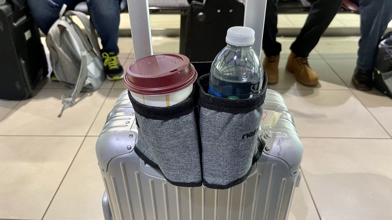 A photo of the Riemot Luggage Travel Cup Holder attached to a Rimowa metal carry-on suitcase