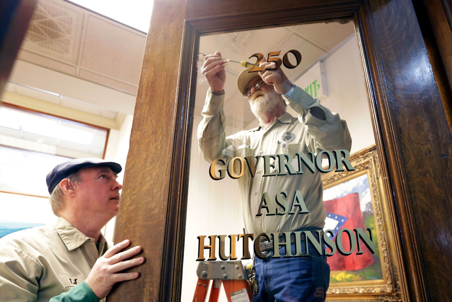 Ronnie Gautney, right, and T.J. Macklin change the glass on the door at the governor's office in Little Rock in January 2015.