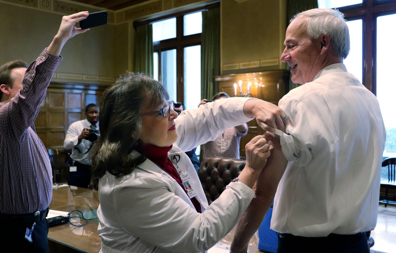Neldia Dycus, the Central Region director of the Arkansas Department of Health, gives Hutchinson a flu shot at the State Capitol in 2017.